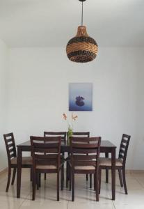 a dining room table with wooden chairs and aendant light at Oasis Apartment in Pereybere +1 photo