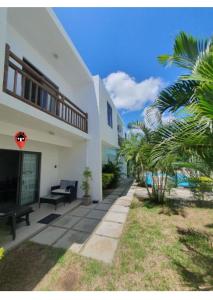 a white house with palm trees in front of it at Oasis Apartment in Pereybere
