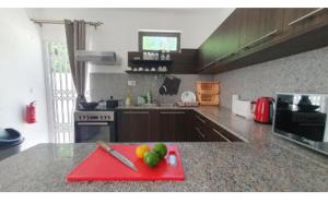 a kitchen with a red cutting board with fruit on it at Oasis Apartment in Pereybere