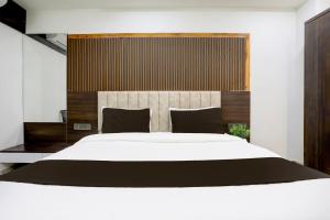 a bedroom with a large white bed with black pillows at Super Hotel O Nana Chiloda Near Airport Formerly Green Valley in Ahmedabad +23 photos