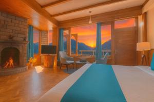 a bedroom with a bed and a fireplace with a view at Hotel Valley View with natural hot spring water Vashisht, Manali in Manāli