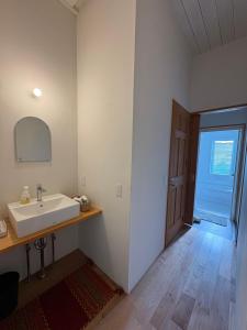 a white bathroom with a sink and a door at 里山のいぶき舎 in Goto