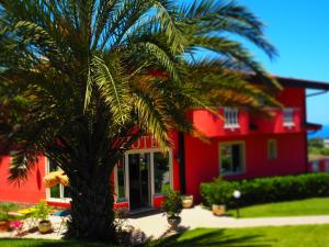 a palm tree in front of a red house at Borgo di Santa Barbara in Santa Domenica