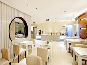 a restaurant with tables and chairs and a kitchen at Magnotel Business Harbin Railway Station Qiulin Museum Metro Station in Harbin