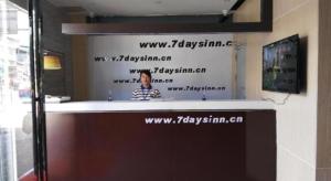 a man standing behind a counter with writing on a wall at 7 Days Inn Duyun Weng'an in Yung-yang