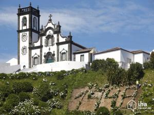 a church with a clock tower on top of a hill at Ribeirinha House in Porto Formoso