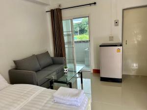 a room with a bed and a couch and a glass table at Takeda - ทาเคดะ in Ban Thok Wak