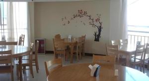 a dining room with tables and chairs and a tree on the wall at GreenTree Inn Linyi Bus Station in Linyi
