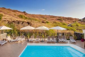 - une piscine avec des chaises longues et des parasols dans l'établissement Tama Hotel, à Saint-Gilles les Bains