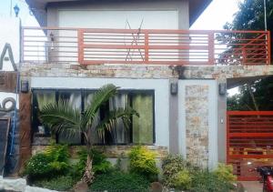 a house with a palm tree in front of it at RedDoorz @ Balay Hiraya Apartment in La Carlota
