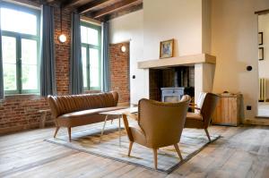 a living room with chairs and a table and a fireplace at 't Schippershuis in Vurste