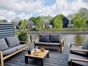 a deck with two couches and a coffee table at Luxurious detached water villa with jetty in Balk