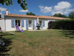 莫雷勒斯Gîte Nénuphar - Gîtes Au Bas Marais的院子里有一栋房子，摆放着紫色椅子和一张桌子。