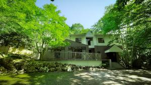 a large white house with a balcony and trees at 來Lai 北軽井沢Resort Villa 158 in Tsumagoi