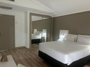 a bedroom with a large white bed and a mirror at Hotel Alfonso I in Tui