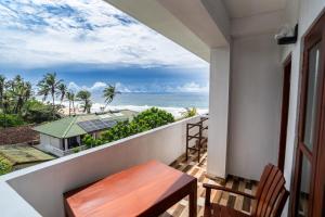 a balcony with a table and chairs and the ocean at Serenade Beach Hotel in Hikkaduwa