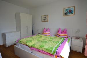 Schlafzimmer mit einem Bett mit rosa und grüner Bettwäsche in der Unterkunft Hannover Nr.4 in Carolinensiel