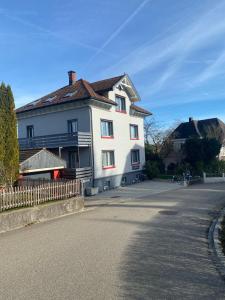 ein weißes Haus mit braunem Dach auf einer Straße in der Unterkunft Dachwohnung in Niederuzwil