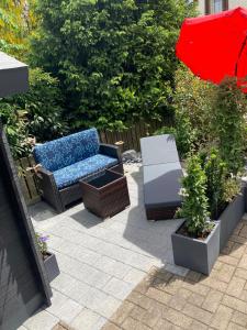 eine Terrasse mit einem Sofa und einem roten Sonnenschirm in der Unterkunft Dachwohnung in Niederuzwil + 2 Fotos