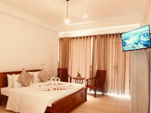 a bedroom with a bed and a flat screen tv at Hotel Helani Pvt Ltd in Midigama East
