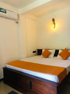 Coco Breeze Villa في تالبي: غرفة نوم مع سرير ووسائد برتقالية عليه