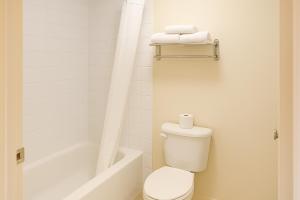 e bagno bianco con servizi igienici e vasca. di Best Maple Inn - Drayton Valley a Drayton Valley Altre 33 foto