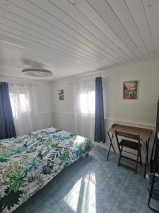 Un dormitorio con una cama y una mesa de madera. en KaZen chez Steph, en Petite Île