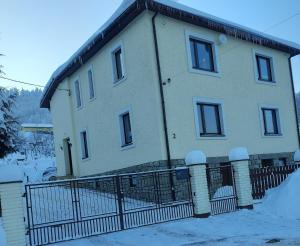 ein Haus mit einem Zaun im Schnee in der Unterkunft Noclegi - Ostre Lipowa Żywiec Beskidy in Ostre
