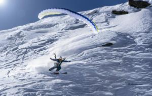 a person is skiing down a snow covered mountain with a parachute at Agriturismo Montespluga in Montespluga