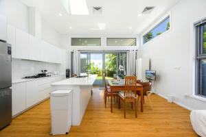 Una cocina con gabinetes blancos y una mesa y sillas. en Modern Riverwood Home with Parking & Easy Access, en Riverwood