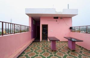 Arun Auro Residency في Kuilapayam: شرفة بها مقعدين في مبنى وردي اللون