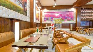 a restaurant with tables and chairs and a painting on the wall at Sumanglam in Dehradun