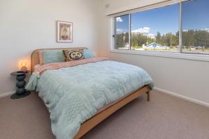 Un dormitorio con una cama y una ventana grande. en Sunset Sisters - Villa Lola & Villa Frankie, en Forster