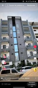 Un gran edificio con coches aparcados delante. en Les merveilles, en Pikine