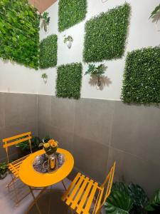 una mesa y sillas junto a una pared con plantas en Les merveilles, en Pikine