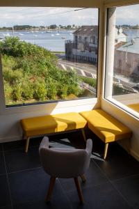 Eine gelbe Bank und ein Stuhl vor einem Fenster in der Unterkunft Jolie maison neuve PMR au port de l'Aberwrac'h in Landéda
