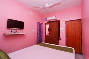 Arun Auro Residency في Kuilapayam: غرفة وردية مع سرير وتلفزيون