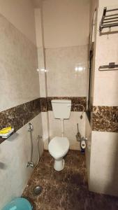 a small bathroom with a toilet and a shower at Riyansh Villa in Gwalior +3 photos
