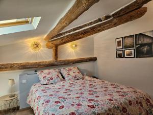 een slaapkamer met een bed en houten balken bij Le nid douillet in Pertuis