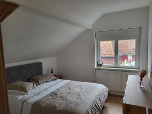 a white bedroom with a bed and a window at Printemps et Eté en Alsace in Stosswihr
