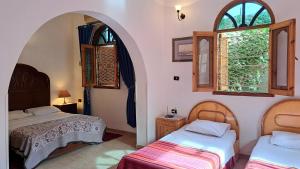 a room with two beds and two windows at Villa Belzoni in Luxor