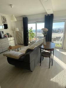ein Wohnzimmer mit Sofa und Tisch in der Unterkunft Studio cocoon avec vue sur le Beaujolais in Mâcon