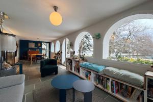 un soggiorno con finestre ad arco e una libreria con libri di Les Nénuphars magnifique villa au bord du canal a Saint-Alban-de-Montbel