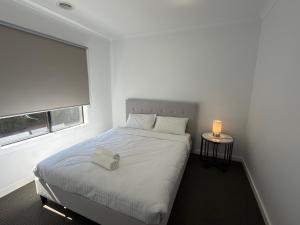 a white bedroom with a bed and a window at Stunning 4 X Bed Holiday Home In Kalkallo! in Kalkallo