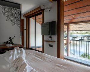 a bedroom with a bed and a tv and a balcony at Mayanadhi Resort in Irimbranallūr