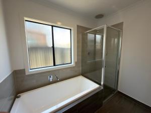 a bathroom with a bath tub and a window at Stunning 4 X Bed Holiday Home In Kalkallo! in Kalkallo +15 photos