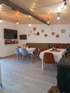 a dining room with tables and chairs and a flat screen tv at Casa din Prund din Porumbacu de sus in Porumbacu de Sus