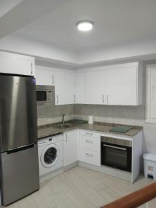 eine Küche mit weißen Schränken und einem Edelstahlkühlschrank in der Unterkunft Apt isabel in Ardales