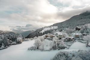 a snow covered village in the mountains with houses at Gasthof Kohlern 1130 m in Bolzano
