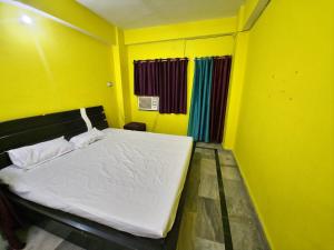 a bedroom with a white bed in a yellow room at mahitra beautiful homestay in Patna